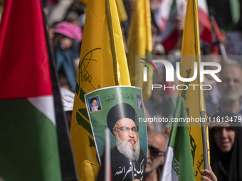 An Iranian worshipper carries a portrait of Lebanon's Hezbollah Secretary General, Hassan Nasrallah, during an anti-Israeli protest to conde...