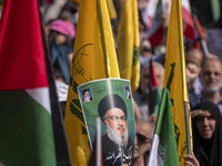 An Iranian worshipper carries a portrait of Lebanon's Hezbollah Secretary General, Hassan Nasrallah, during an anti-Israeli protest to conde...