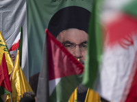 Iranian worshippers wave a Palestinian flag and an Iranian flag in front of a portrait of Lebanon's Hezbollah Secretary General, Hassan Nasr...