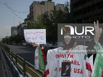 An Iranian female protester, wearing a shroud covered with anti-U.S. and anti-Israeli slogans and a portrait of Iran's Supreme Leader Ayatol...