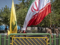 Islamic Revolutionary Guard Corps (IRGC) military personnel and schoolboys carry an Iranian flag and a flag of Lebanon's Hezbollah before an...