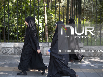 Veiled Iranian worshippers walk along a sidewalk to the University of Tehran to take part in a Friday prayers ceremony before an anti-Israel...