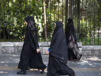 Veiled Iranian worshippers walk along a sidewalk to the University of Tehran to take part in a Friday prayers ceremony before an anti-Israel...