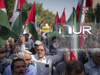 An Iranian worshipper carries a portrait of Lebanon's Hezbollah Secretary General, Hassan Nasrallah, during an anti-Israeli protest to conde...