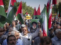 An Iranian worshipper carries a portrait of Lebanon's Hezbollah Secretary General, Hassan Nasrallah, during an anti-Israeli protest to conde...