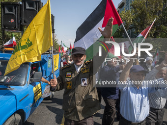 An Iranian worshipper wearing a fake military uniform carries a Lebanon Hezbollah flag while shouting anti-Israeli slogans as he takes part...