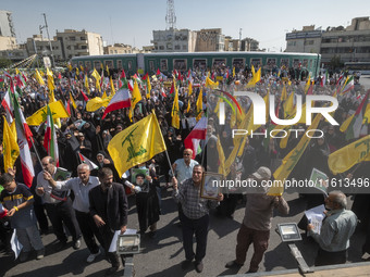 Iranian worshippers wave Lebanon's Hezbollah flags while taking part in an anti-Israeli protest to condemn Israel's military attack on Leban...