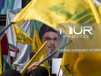 Iranian worshippers wave Lebanon's Hezbollah flags in front of a portrait of the Hezbollah Secretary General, Hassan Nasrallah, during an an...