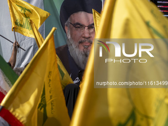 Iranian worshippers wave Lebanon's Hezbollah flags in front of a portrait of the Hezbollah Secretary General, Hassan Nasrallah, during an an...