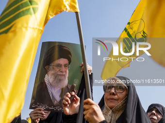 Iranian worshippers wave Lebanon's Hezbollah flags as one of them holds a portrait of Iran's Supreme Leader, Ayatollah Ali Khamenei, while t...