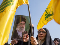 Iranian worshippers wave Lebanon's Hezbollah flags as one of them holds a portrait of Iran's Supreme Leader, Ayatollah Ali Khamenei, while t...