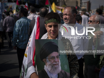 A young member of the Basij Paramilitary Force holds a portrait of Iran's Supreme Leader, Ayatollah Ali Khamenei, while taking part in an an...