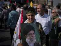 A young member of the Basij Paramilitary Force holds a portrait of Iran's Supreme Leader, Ayatollah Ali Khamenei, while taking part in an an...