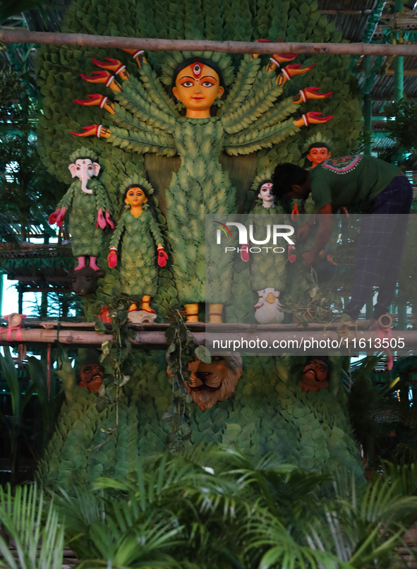 An artisan decorates an idol of the Hindu goddess Durga with eight thousand natural plants to raise awareness about global deforestation, cl...