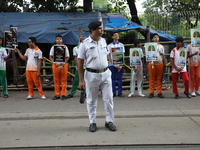 A police officer stands guard while school students make a human chain and hold posters during a Global Climate Strike march in Kolkata, Ind...