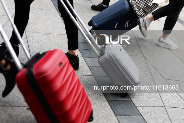 People walk with suitcases in Krakow, Poland on September 26, 2024. 