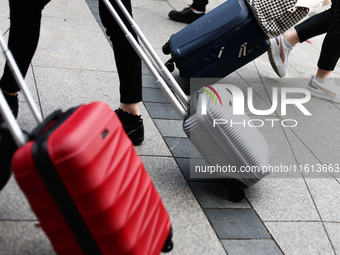 People walk with suitcases in Krakow, Poland on September 26, 2024. (