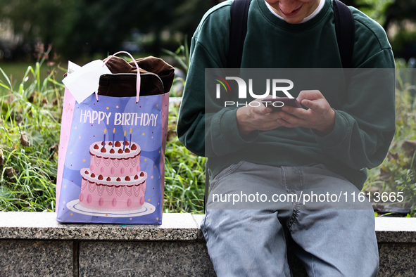 A person uses a phone as a birthday gift bag is seen in Krakow, Poland on September 26, 2024. 