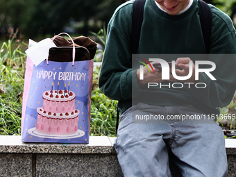 A person uses a phone as a birthday gift bag is seen in Krakow, Poland on September 26, 2024. (