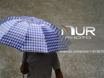 A pedestrian travels in heavy rainfall with an umbrella in Kirtipur, Kathmandu, Nepal, on September 27, 2024. (