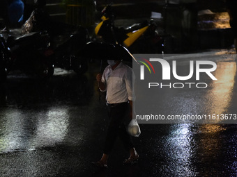 A pedestrian travels in heavy rainfall with an umbrella in Kirtipur, Kathmandu, Nepal, on September 27, 2024. (