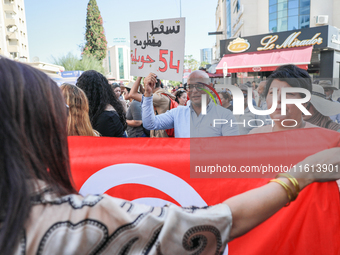 A demonstrator raises a placard that reads in Arabic, ''Down with the 54 July system,'' during a demonstration organized by the Tunisian Net...