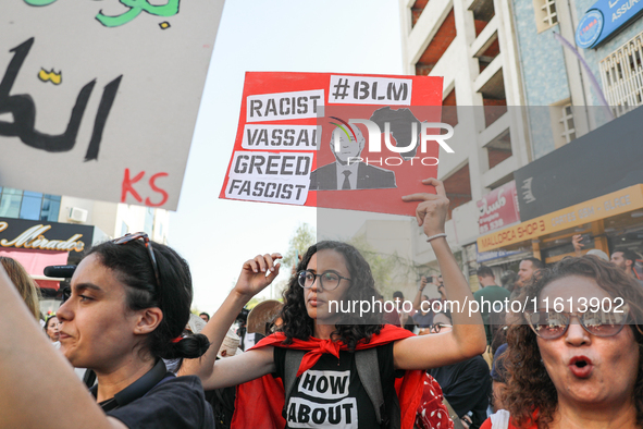 A female demonstrator raises a placard with a caricature of Tunisian President Kais Saied that reads, ''racist, vassal, greed, fascist,'' du...