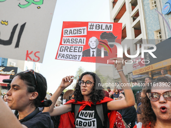 A female demonstrator raises a placard with a caricature of Tunisian President Kais Saied that reads, ''racist, vassal, greed, fascist,'' du...