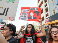 A female demonstrator raises a placard with a caricature of Tunisian President Kais Saied that reads, ''racist, vassal, greed, fascist,'' du...