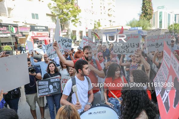 Tunisians shout slogans and raise placards during a demonstration organized by the Tunisian Network for Rights and Freedoms near the Assembl...