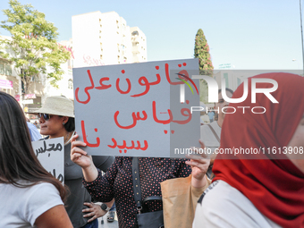 A demonstrator holds a placard that reads in Arabic, ''a law tailored to the President,'' during a demonstration organized by the Tunisian N...