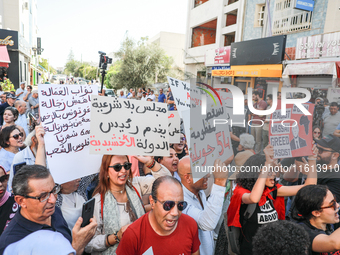 Tunisians shout slogans and raise placards during a demonstration organized by the Tunisian Network for Rights and Freedoms near the Assembl...