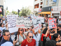 Tunisians shout slogans and raise placards during a demonstration organized by the Tunisian Network for Rights and Freedoms near the Assembl...