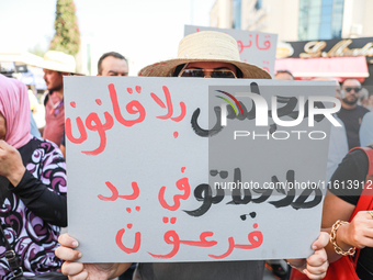 A female demonstrator raises a placard that reads in Arabic, ''a lawless Parliament at the mercy of pharaoh,'' during a demonstration organi...