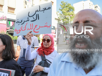 A female demonstrator raises a placard that reads in Arabic, ''The Parliament of illegitimacy legalizes dictatorship,'' during a demonstrati...