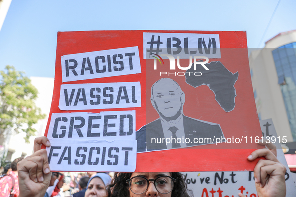 A female demonstrator raises a placard with a caricature of Tunisian President Kais Saied that reads, ''racist, vassal, greed, fascist,'' du...