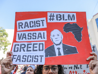 A female demonstrator raises a placard with a caricature of Tunisian President Kais Saied that reads, ''racist, vassal, greed, fascist,'' du...