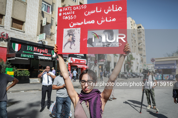 A female demonstrator holds up a placard with photos of sub-Saharan African migrants who die in the desert during a demonstration organized...