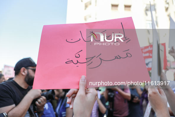 A demonstrator holds a placard that reads in Arabic, ''theatrical elections,'' during a demonstration organized by the Tunisian Network for...