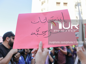 A demonstrator holds a placard that reads in Arabic, ''theatrical elections,'' during a demonstration organized by the Tunisian Network for...