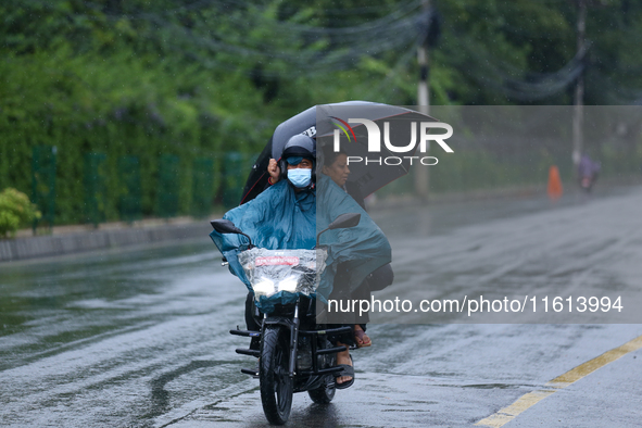 Drivers wear raincoats and carry umbrellas after incessant rainfall in Kathmandu, Nepal, on September 27, 2024, following a red alert issued...