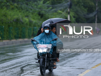 Drivers wear raincoats and carry umbrellas after incessant rainfall in Kathmandu, Nepal, on September 27, 2024, following a red alert issued...