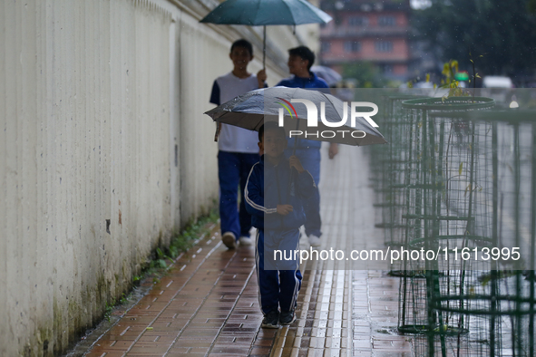 A Nepali student carries an umbrella as she walks towards the school in Nepal on September 27, 2024, following a red alert issued by the wea...