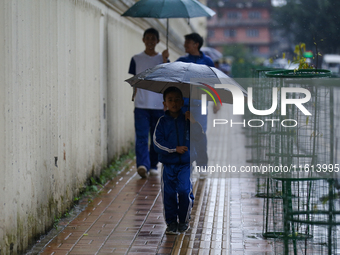 A Nepali student carries an umbrella as she walks towards the school in Nepal on September 27, 2024, following a red alert issued by the wea...