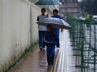 A Nepali student carries an umbrella as she walks towards the school in Nepal on September 27, 2024, following a red alert issued by the wea...