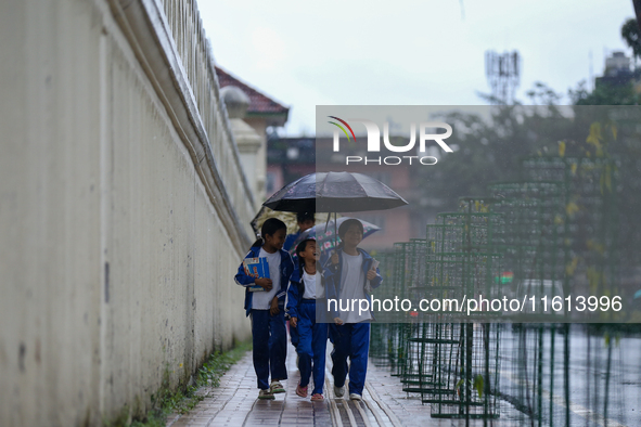 A Nepali student wears an umbrella as she walks towards the school as the incessant rainfall continues following a red-alert issued by the w...