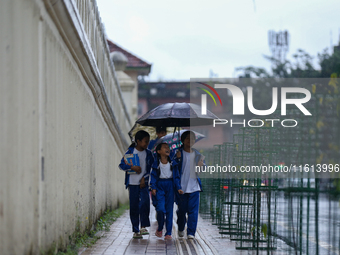 A Nepali student wears an umbrella as she walks towards the school as the incessant rainfall continues following a red-alert issued by the w...