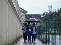 A Nepali student wears an umbrella as she walks towards the school as the incessant rainfall continues following a red-alert issued by the w...