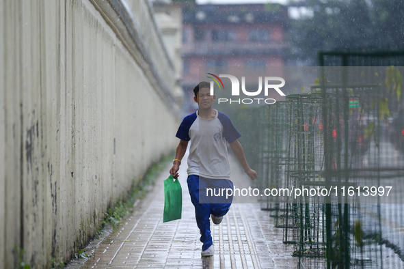 A Nepali student runs towards his home from school amid the downpour in Kathmandu, Nepal, on September 27, 2024. The Himalayan nation witnes...