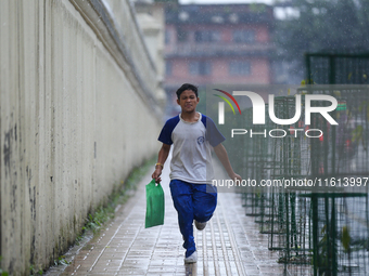 A Nepali student runs towards his home from school amid the downpour in Kathmandu, Nepal, on September 27, 2024. The Himalayan nation witnes...